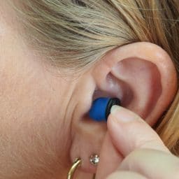 Woman inserts earplugs into her ears.