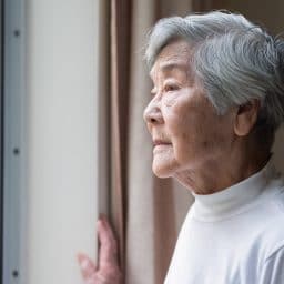 Older woman looking outside a window.