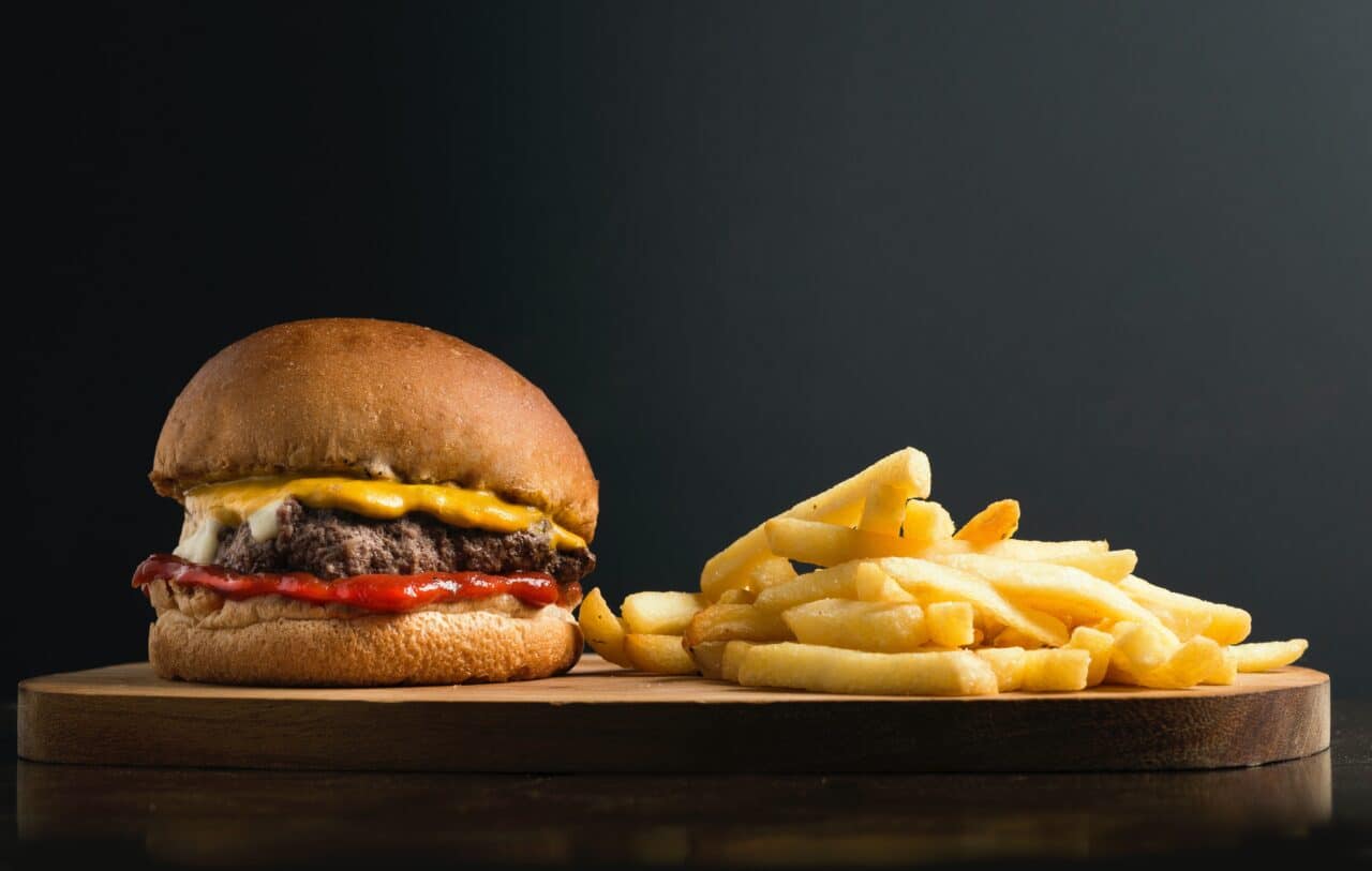 Cheeseburger and fries in front of a black background.