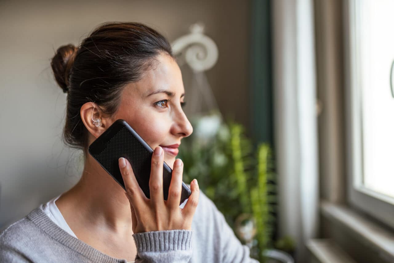 Woman with a hearing aid talking on phone.