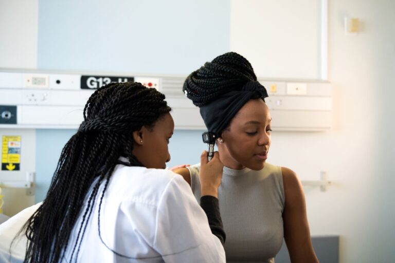 ENT diagnosing an earache female doctor looking in female patients ear with a medical device to identify indications of an earache
