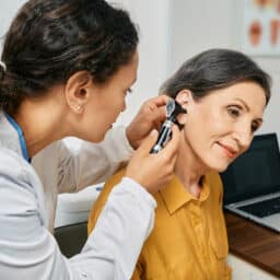 Senior woman receiving an ear exam from an audiologist.