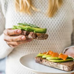 Woman holding avocado toast with salmon, omega-3s