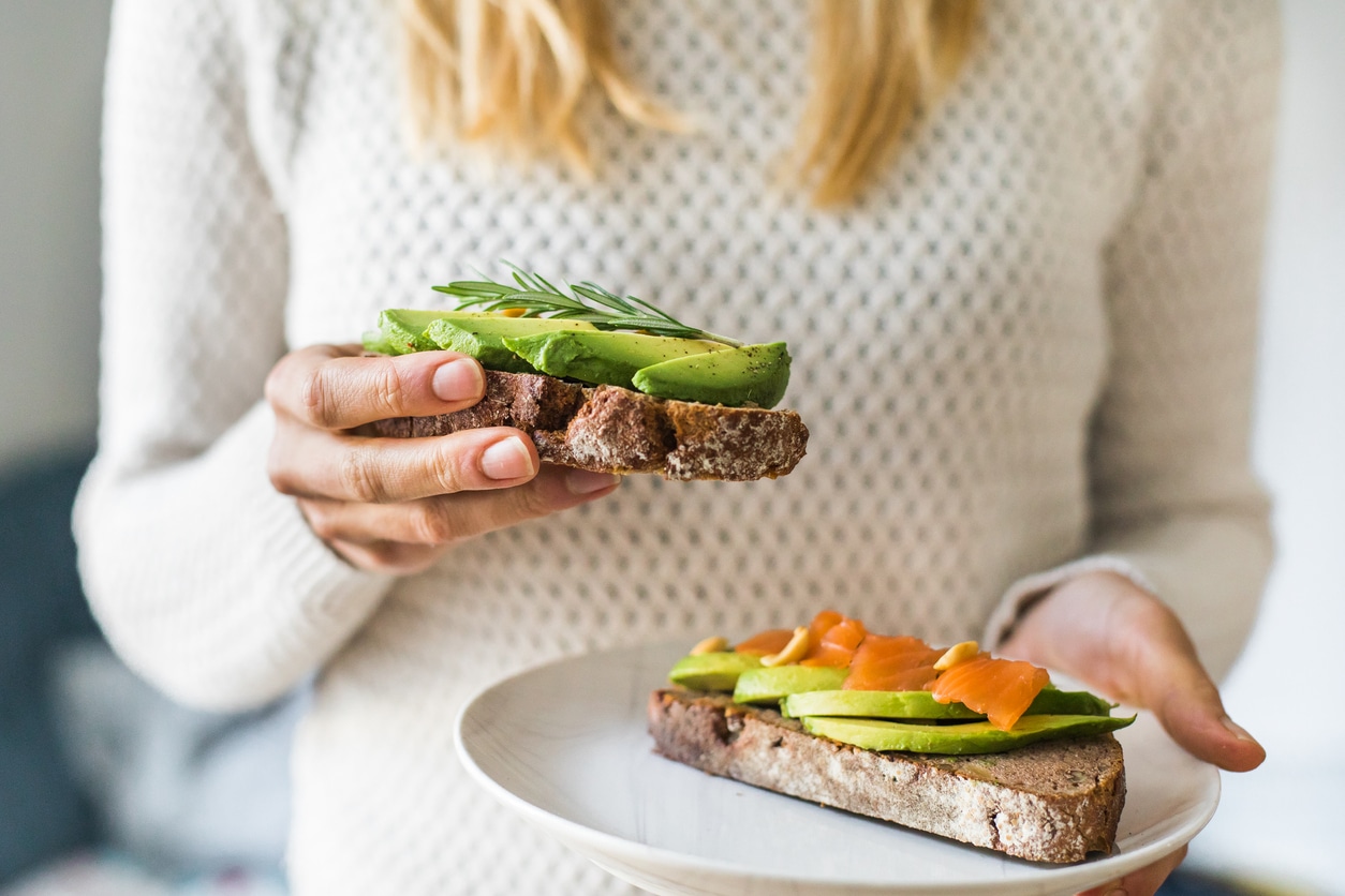 Woman holding avocado toast with salmon, omega-3s