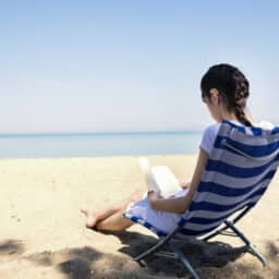 Woman wearing a hearing aid reading on the beach