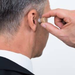 Person in a suit inserting a hearing aid