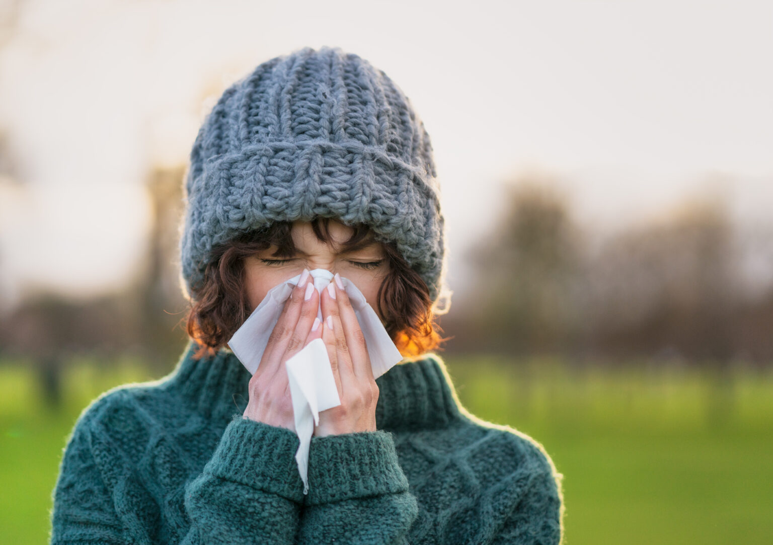 A woman sick with a virus blows her nose.