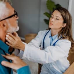 ENT examines a patient's thyroid