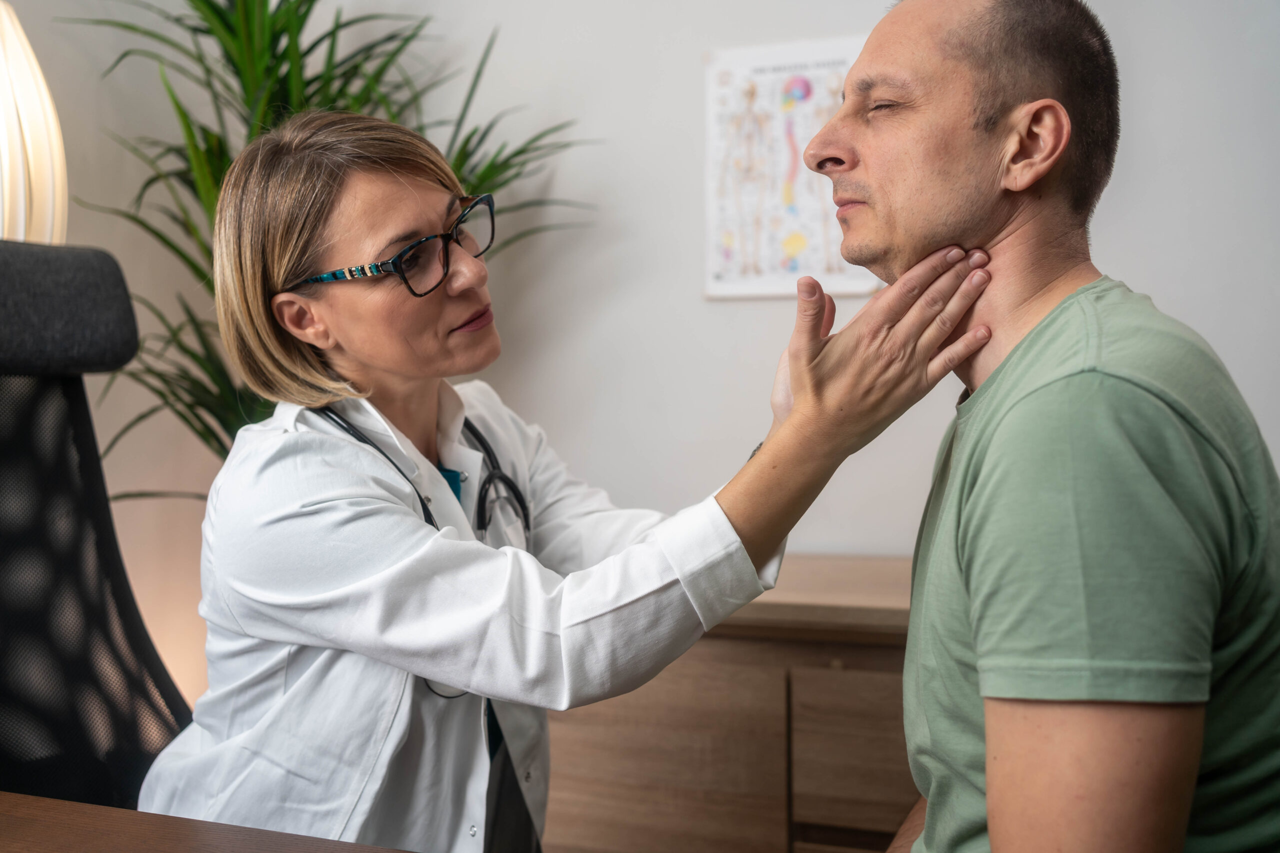 Doctor examines her patient's thyroid.