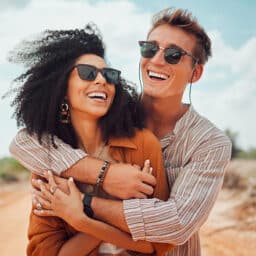 Stylish couple wearing sunglasses and hugging.