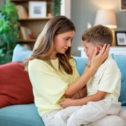 Woman examines her son who is complaining of ear pain.
