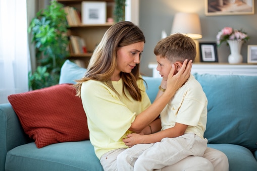 Woman examines her son who is complaining of ear pain.